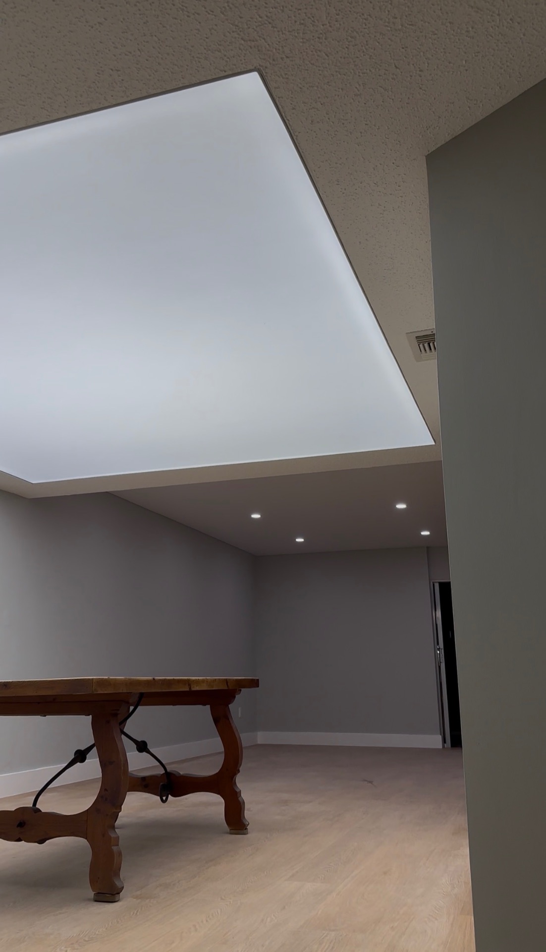 Close-up detail of stretch ceiling installation showing luminous panel and recessed lighting